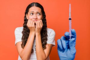 ragazza impaurita e siringa con ago
